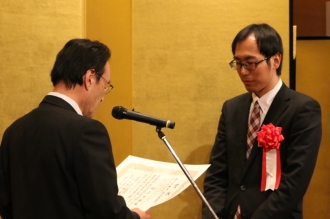 授賞式で表彰状を授与される村上大輔特別研究員